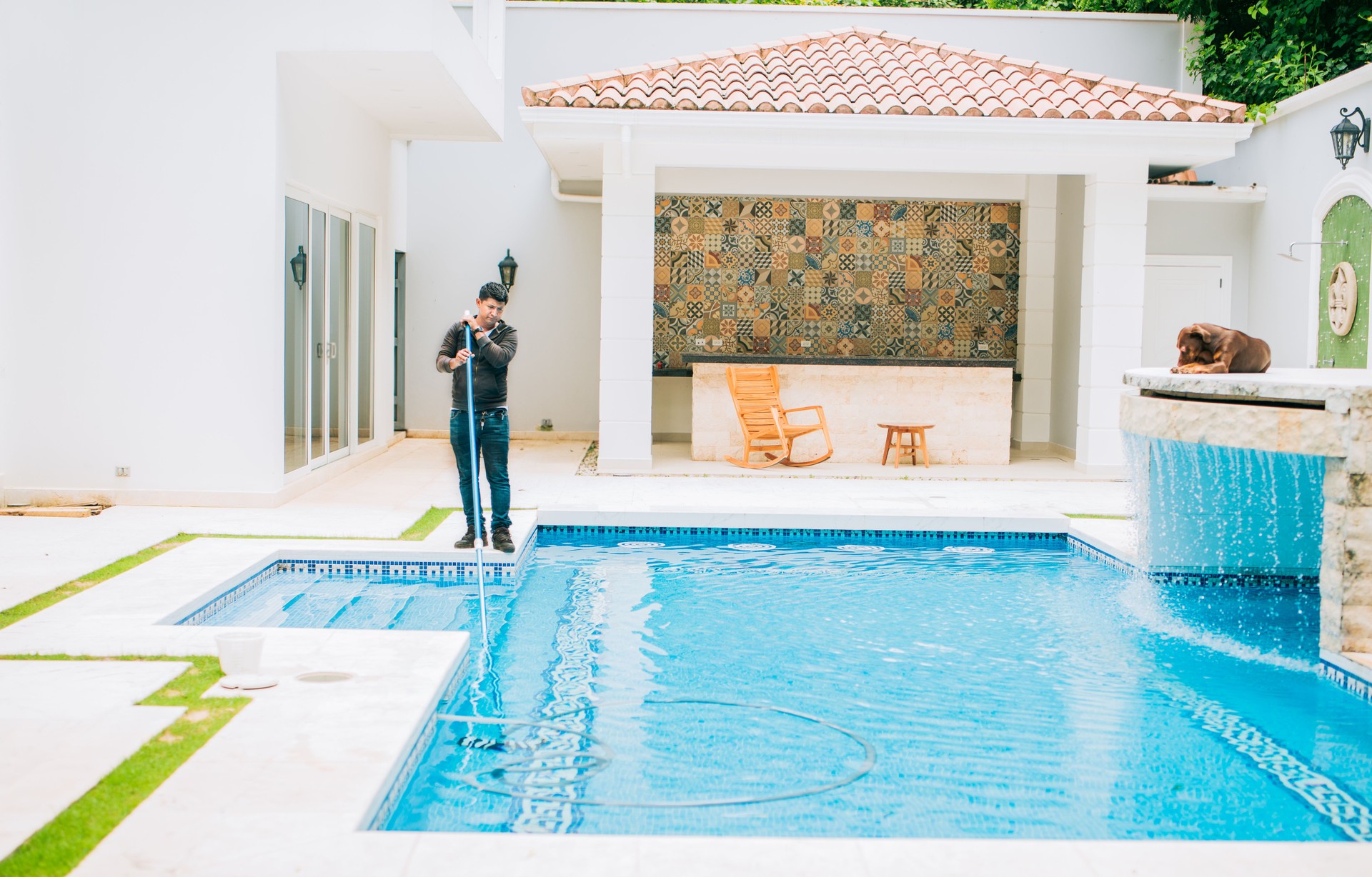 Swimming pool cleaning and maintenance service. Pool maintenance and cleaning with vacuum hose. Young man cleaning pool with suction hose